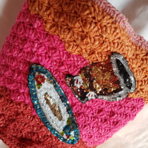 Bolso de crochet de combinaciones de colores, forrado con tela de loneta, y aplicaciones de plarto y taza de paillete