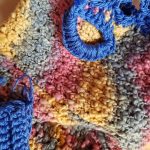 Detalle del bolso de crochet tejido a punto de red, combinación de colores, forrado por la parte superior con tela estampada y bolso de mano de conjunto