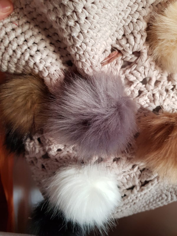 Detalle de la bolsa grande de crochet con hilo de algodon, forrada con tela dd loneta y 10 pompones de colores naturales con asa de terciopelo